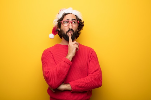 Young crazy bearded man wearing red glasses and santa claus hat 