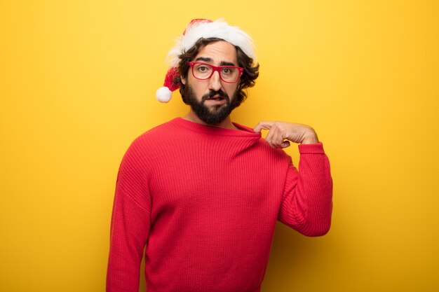 Молодой сумасшедший бородатый мужчина в красных очках и шляпе Санта-Клауса