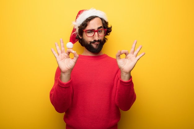 Young crazy bearded man wearing red glasses and santa claus hat 