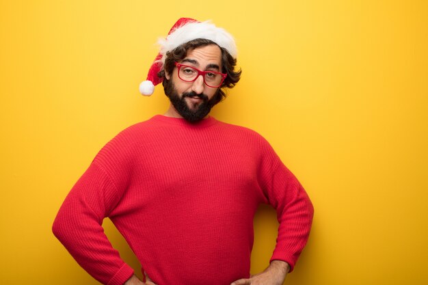 Young crazy bearded man wearing red glasses and santa claus hat 