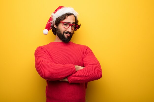 Young crazy bearded man wearing red glasses and santa claus hat 