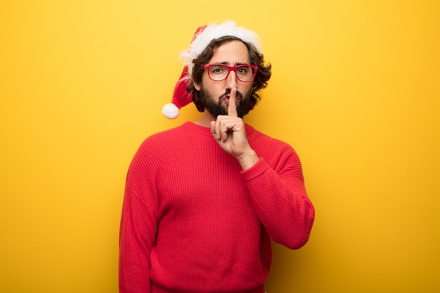 Young crazy bearded man wearing red glasses and santa claus hat 