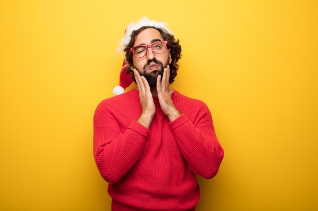 Young crazy bearded man wearing red glasses and santa claus hat 