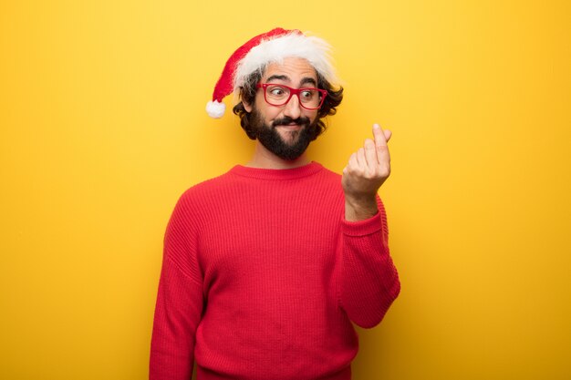 Young crazy bearded man wearing red glasses and santa claus hat 