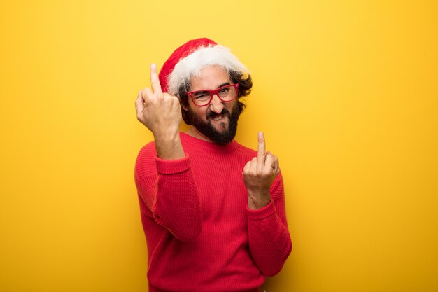 Young crazy bearded man wearing red glasses and santa claus hat 