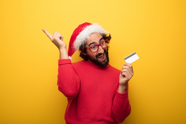 Young crazy bearded man wearing red glasses and santa claus hat 