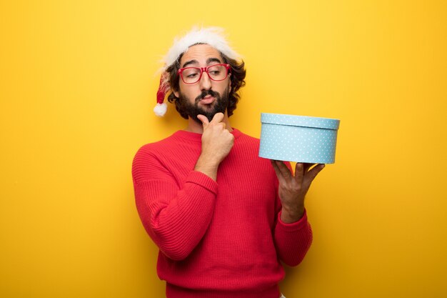 Young crazy bearded man wearing red glasses and santa claus hat 