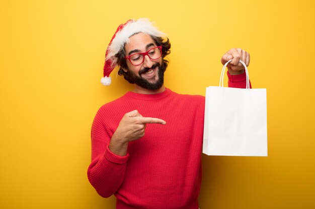 Young crazy bearded man wearing red glasses and santa claus hat 