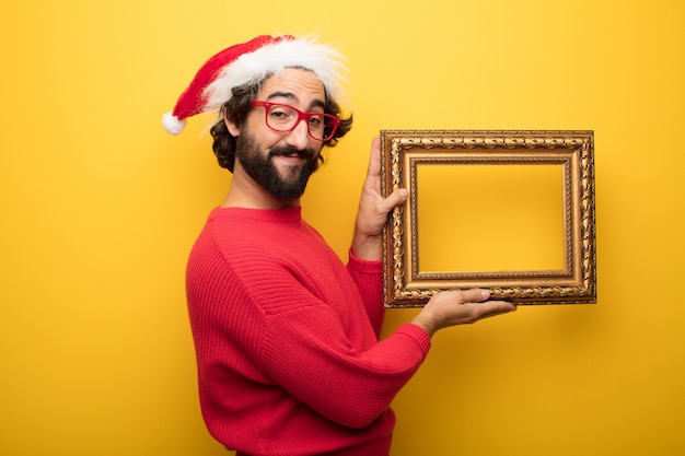 Молодой сумасшедший бородатый мужчина в красных очках и шляпе Санта-Клауса