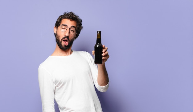 Giovane uomo barbuto pazzo con una birra