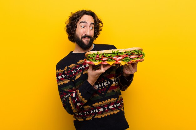 Young crazy bearded man with a giant sandwich.