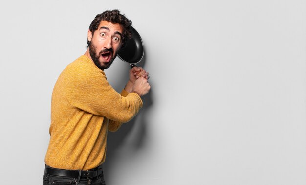 Young crazy bearded man with a pan. cook concept