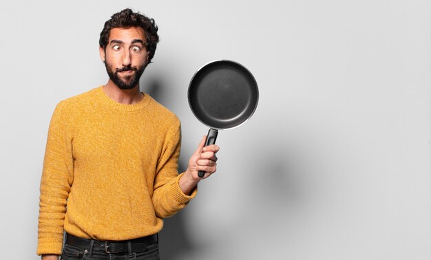 Young crazy bearded man with a pan. cook concept