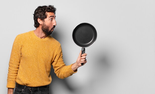 Young crazy bearded man with a pan. cook concept