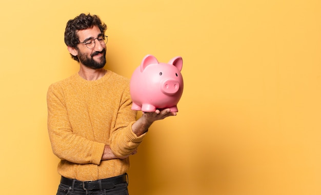 Young crazy bearded man with a piggy bank