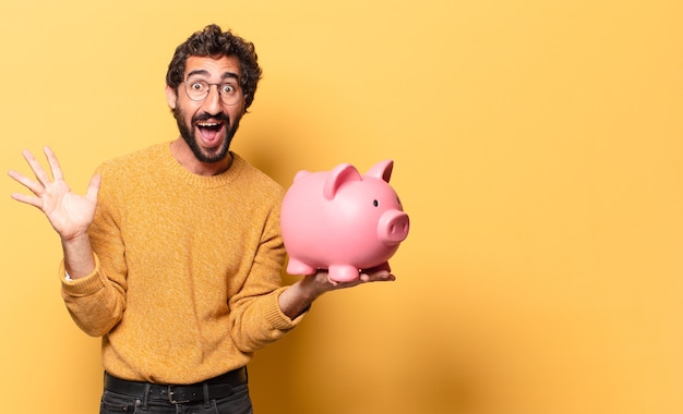 Young crazy bearded man with a piggy bank