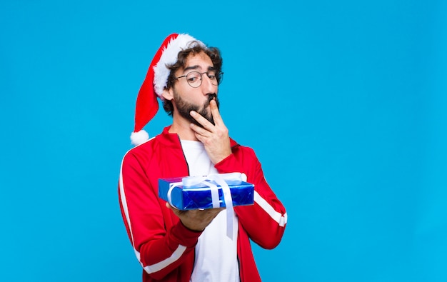 サンタの帽子を持つ若い狂気のひげを生やした男。クリスマスのコンセプト