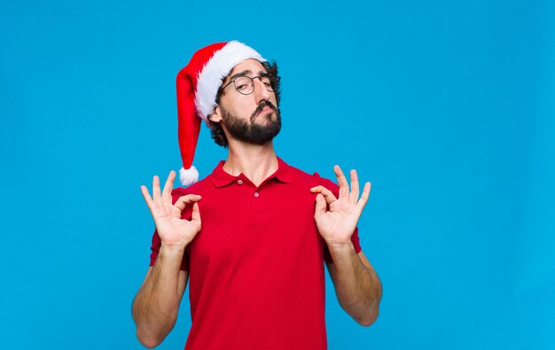 サンタの帽子を持つ若い狂気のひげを生やした男。クリスマスのコンセプト