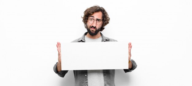 Photo young crazy cool man holding a placard against white wall