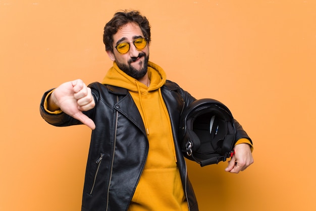 Young crazy cool man rider, holding a motorbike helmet.