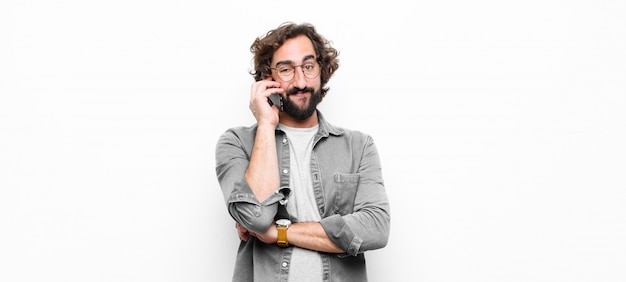 Young crazy cool man using his smartphone against white wall