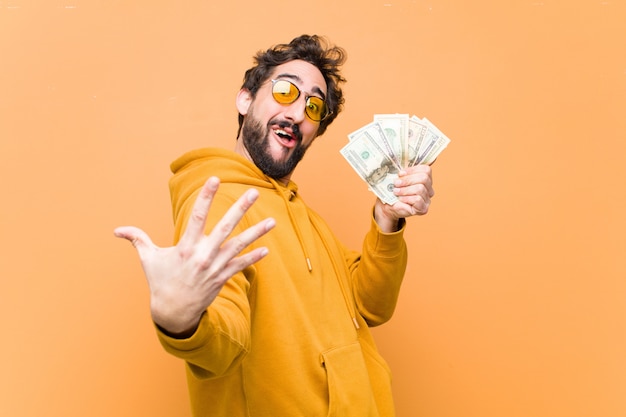 Photo young crazy cool man with dollar banknotes against orange wall