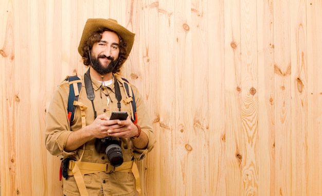 Young crazy explorer with straw hat and backpack on wood background