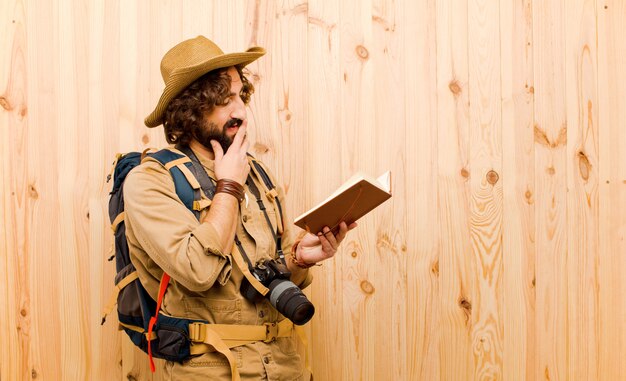 Foto giovane esploratore pazzo con il cappello di paglia e lo zaino su fondo di legno