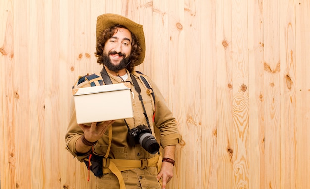 Foto giovane esploratore pazzo con il cappello di paglia e lo zaino su fondo di legno