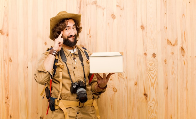 Foto giovane esploratore pazzo con il cappello di paglia e lo zaino su fondo di legno