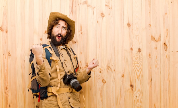 Foto giovane esploratore pazzo con cappello di paglia e zaino sulla parete di legno