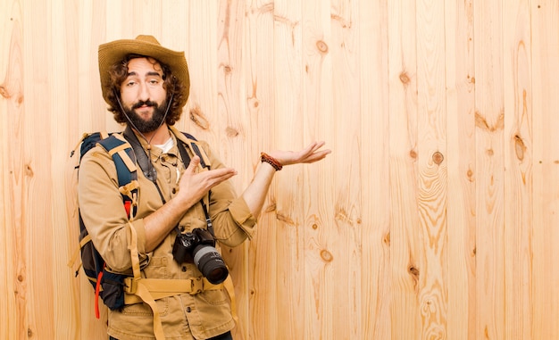 Foto giovane esploratore pazzo con cappello di paglia e zaino sulla parete di legno