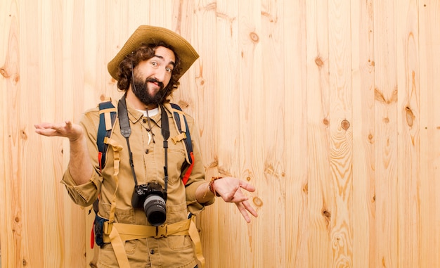 Foto giovane esploratore pazzo con cappello di paglia e zaino sulla parete di legno