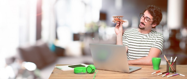 Young crazy graphic designer on a desk with a laptop 