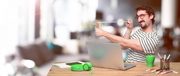 Young crazy graphic designer on a desk with a laptop 