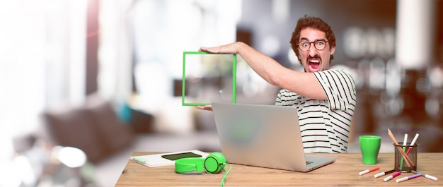 Young crazy graphic designer on a desk with a laptop 