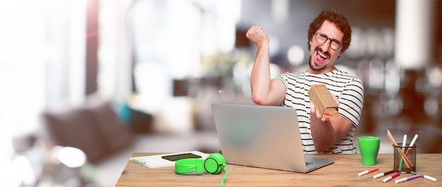 Young crazy graphic designer on a desk with a laptop 