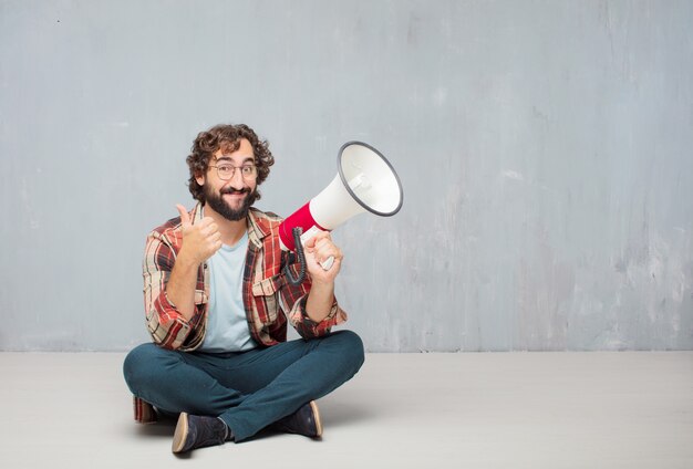 Young crazy mad man fool pose with a megaphone. 