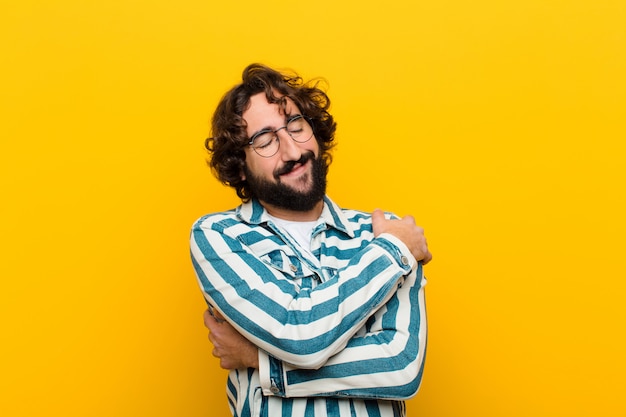 Photo young crazy man feeling in love, smiling, cuddling and hugging self, staying single, being selfish and egocentric  yellow wall