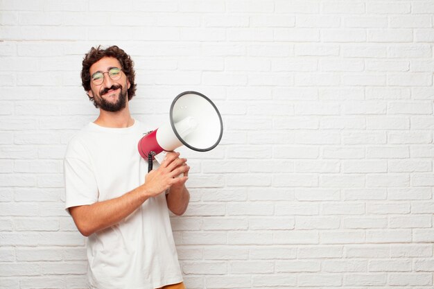 Young crazy man with a megaphone against brick wall.