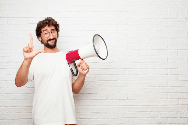 Young crazy man with a megaphone against brick wall.