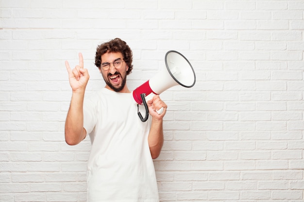 Young crazy man with a megaphone against brick wall.