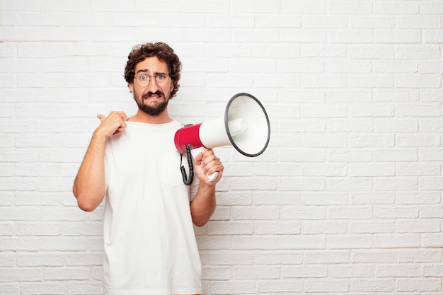 Young crazy man with a megaphone against brick wall.