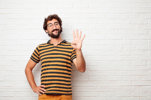 Young crazy or silly man gesturing and expressing emotions against brick wall background
