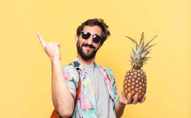 Young crazy traveler man celebrating successful a victory and holding a pineapple