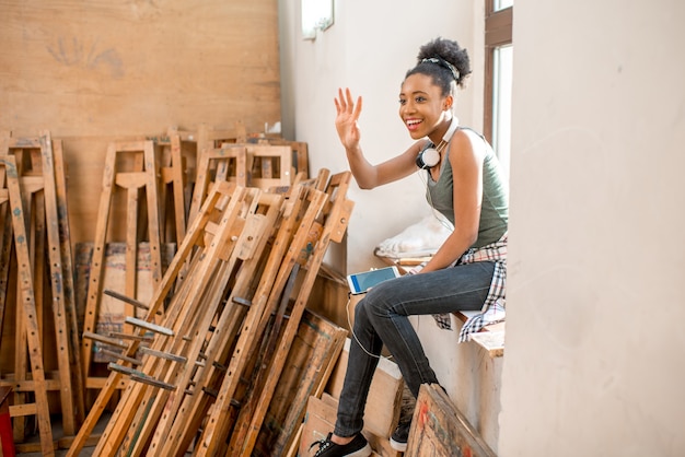 Young creative african ethnicity student sitting on the window during the break at the university studio for painting