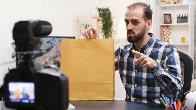 Young creative content creator recording a giveaway on his vlog. Famous influencer.