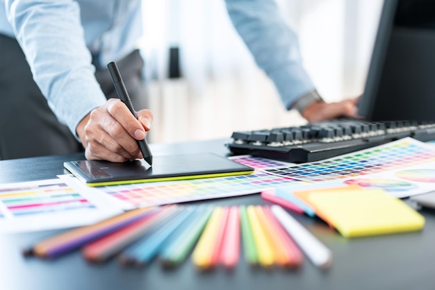 Young creative graphic designer working on color selection and drawing on graphics tablet at workplace Color swatch samples chart for selection coloring