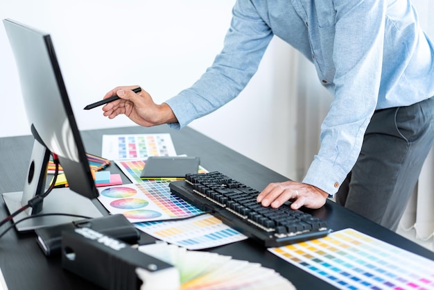 Young creative graphic designer working on color selection and drawing on graphics tablet at workplace Color swatch samples chart for selection coloring