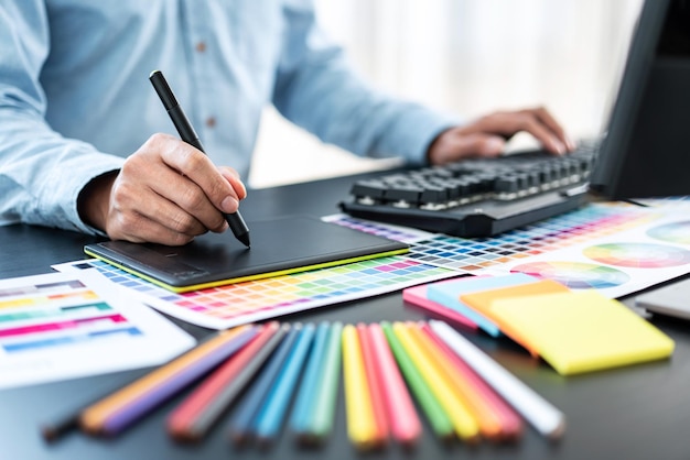 Молодой креативный графический дизайнер работает над выбором цвета и рисует на графическом планшете на рабочем месте Таблица образцов цветов для выбора окраски